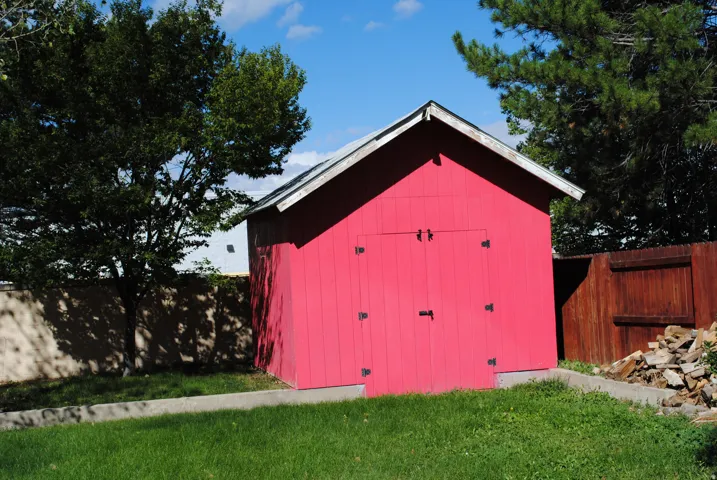 Red shed with double doors and a pitched roof, situated on concrete footings.
