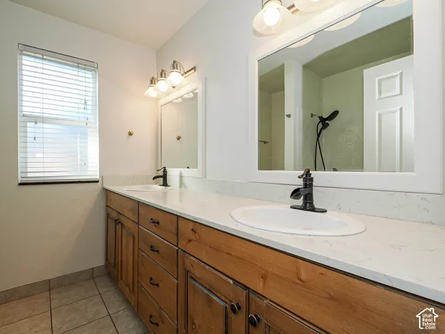 Double vanity featuring wood-finish cabinetry, white stone-composite countertop, dual undermount sinks, matte black faucets, and rectangular framed mirrors
