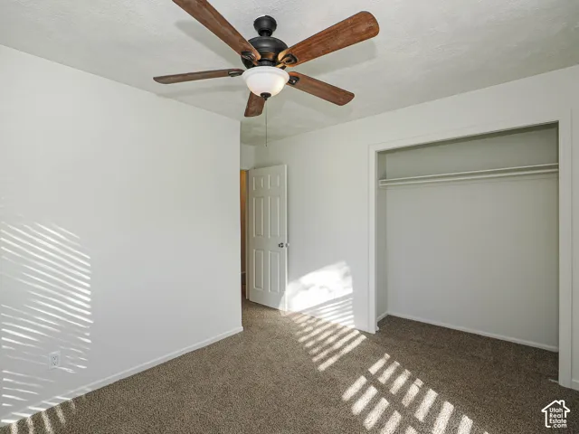 Room featuring neutral carpeting, a ceiling fan with integrated lighting, and a closet with a built-in shelf