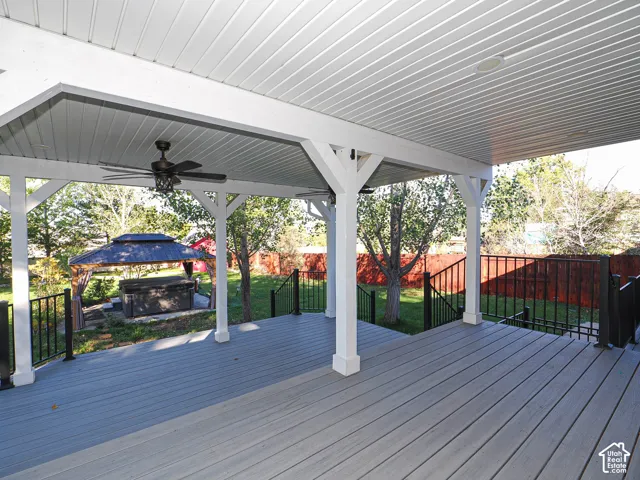 Covered deck featuring composite decking, white structural posts, recessed lighting, ceiling fans, and black metal railings