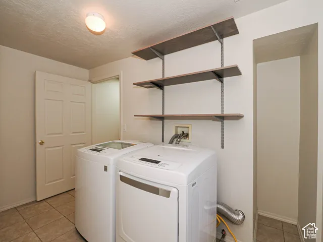Laundry area featuring tiled flooring, three-tier wall-mounted shelving, and a flush-mount ceiling fixture