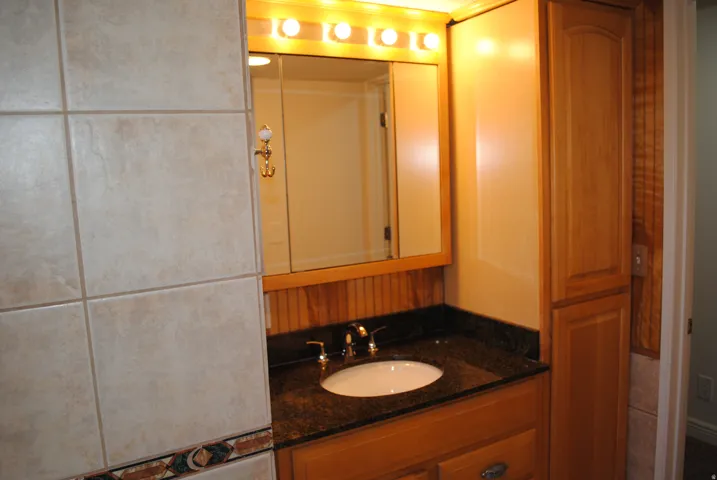 Vanity with granite countertop, integrated sink, and wood cabinetry