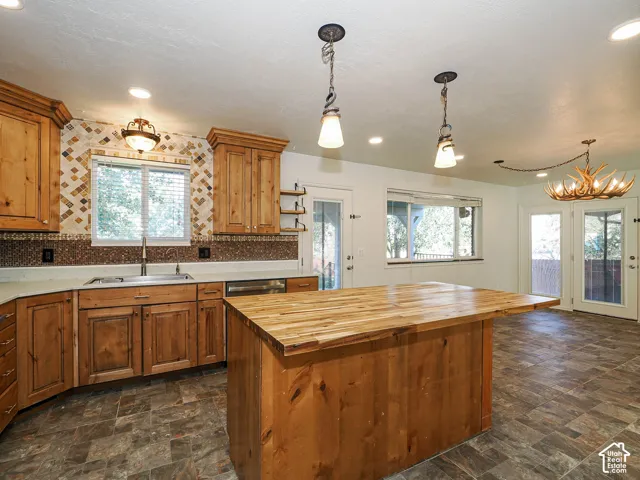 Kitchen featuring stained wood cabinetry, butcher-block kitchen island, decorative tile backsplash, recessed lighting, and tile flooring