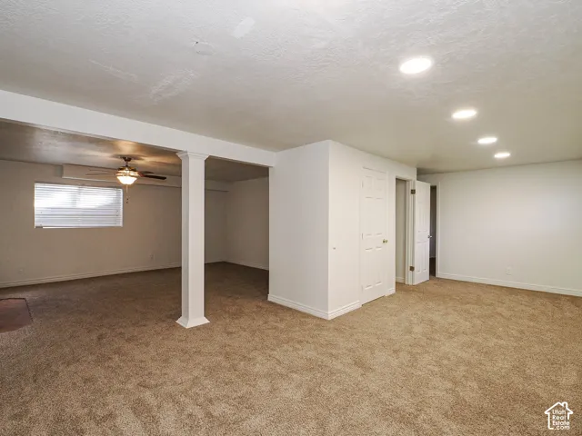 Interior space featuring neutral-toned carpeting, recessed ceiling lighting, a structural support column, and a ceiling fan with integrated lighting