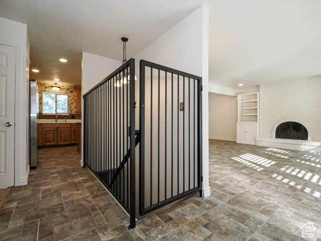 Interior space featuring custom black metal gate, stone-tile flooring, white brick fireplace with arched hearth, and  white cabinetry