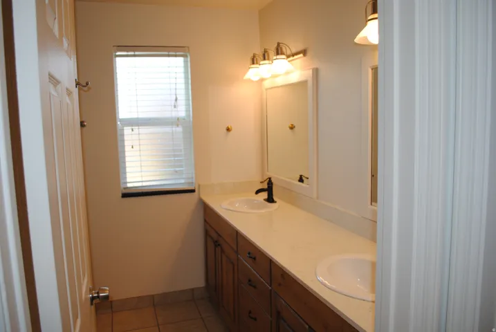 Dual vanity with  sinks, wood-finish cabinetry, and matte black fixtures