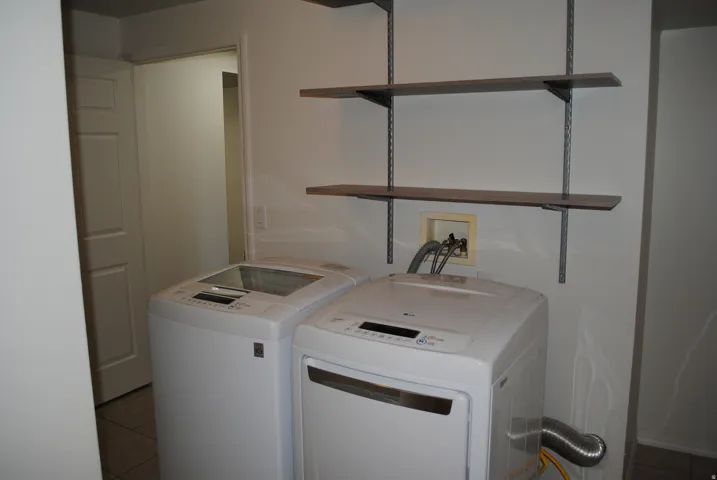 Functional laundry area featuring track-mounted shelving and tile flooring