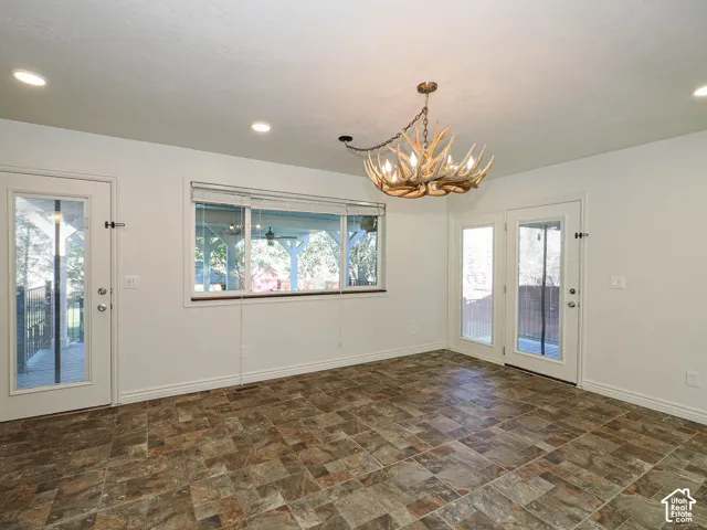 Tile flooring, recessed lighting, antler-style chandelier, and two glass-paneled doors