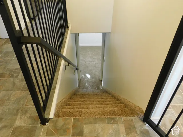 Tiled flooring, carpeted stairs, and a black  railing system