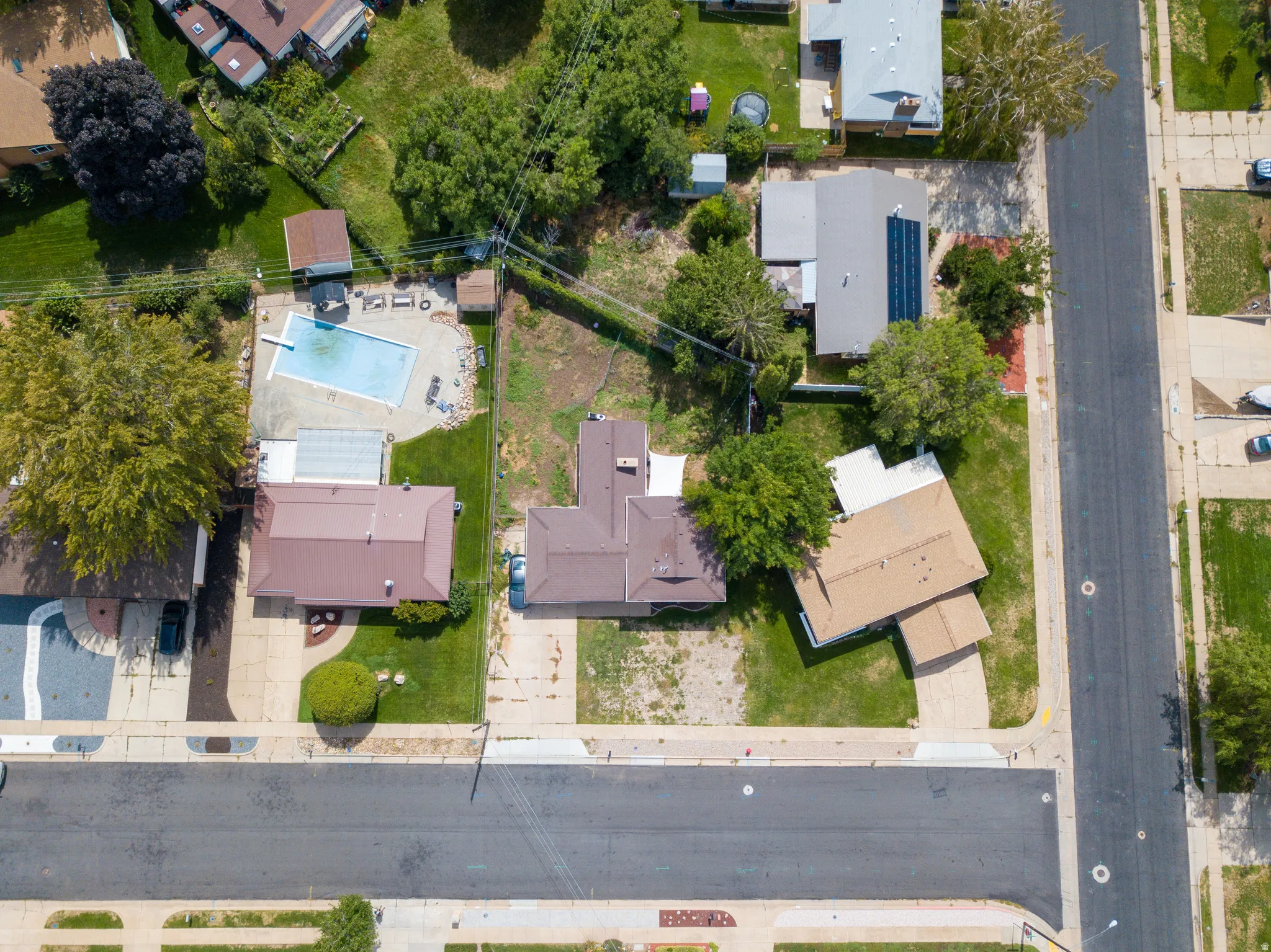 Expansive lot featuring a primary residence with a brown roof and a large, open yard space