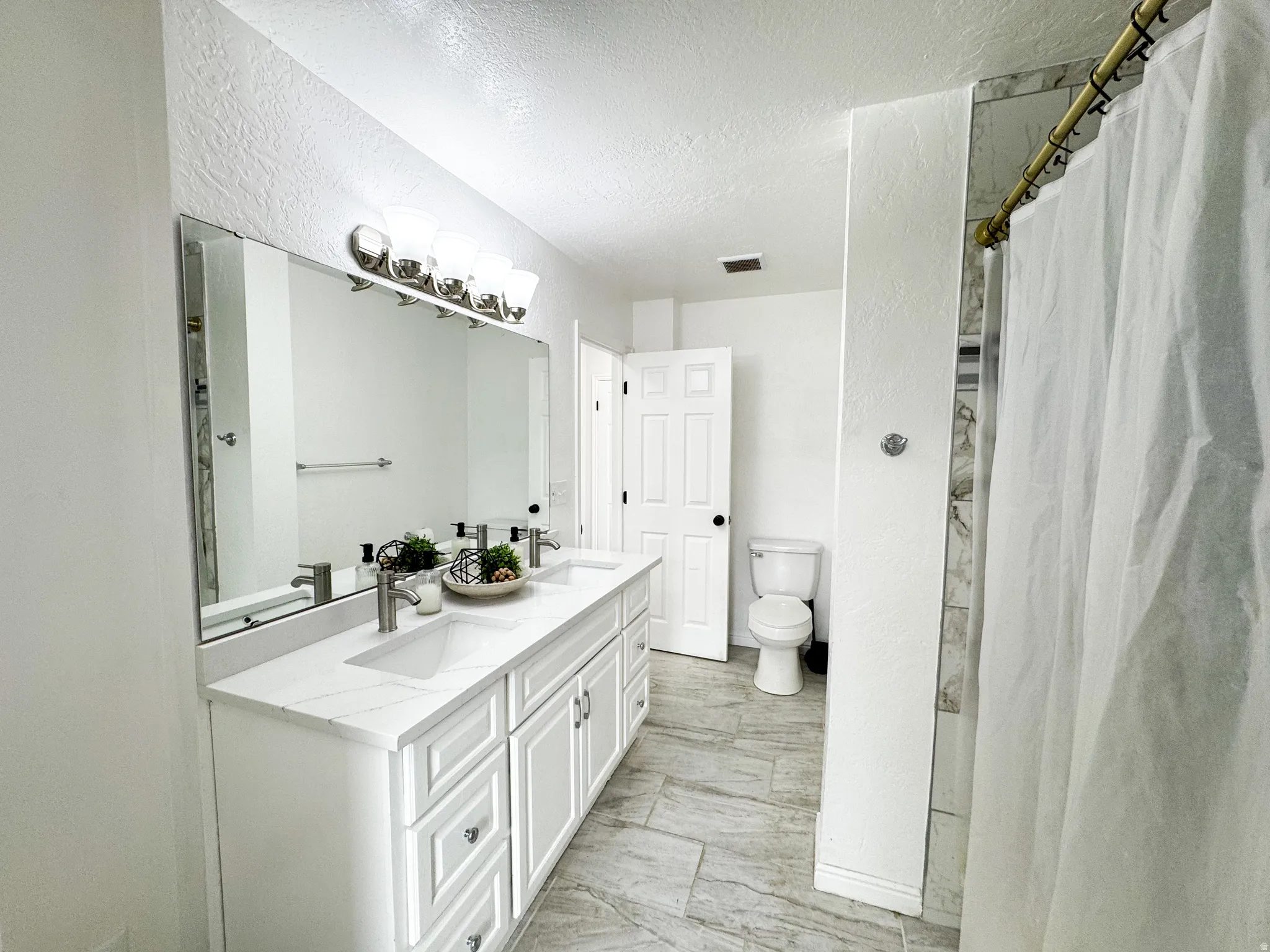 Dual vanity with integrated sinks, brushed nickel fixtures, and a large frameless mirror
