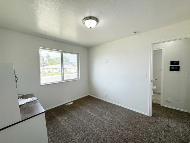 Recessed lighting, neutral wall paint, carpeted flooring, and a window with a neighborhood perspective