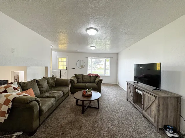 Carpeted living space with a white painted finish, featuring recessed lighting and a window with a white frame