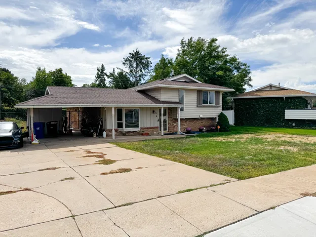 Split-level property featuring a covered carport, concrete driveway, and front lawn