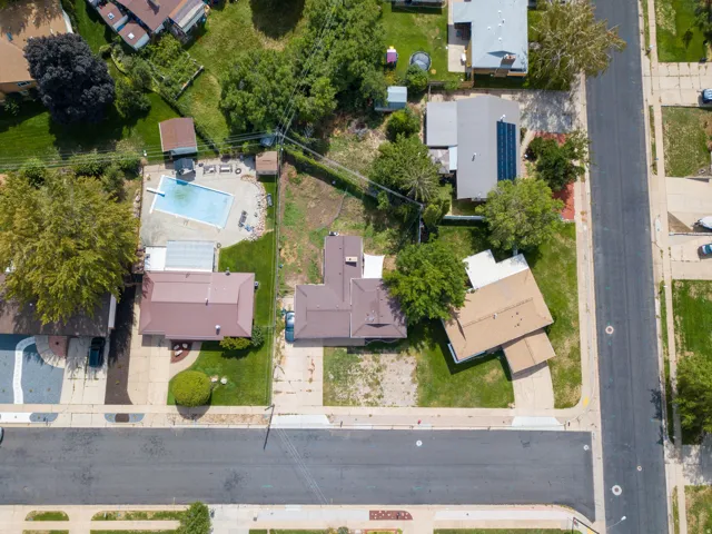 Expansive lot featuring a primary residence with a brown roof and a large, open yard space
