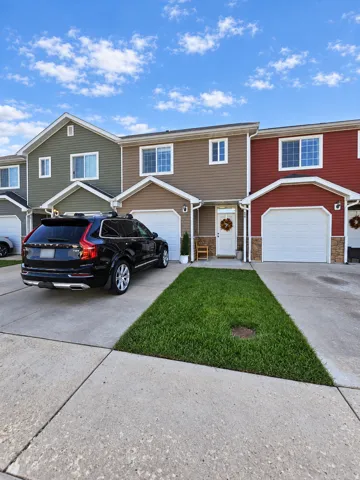 Two-story exterior with siding, attached garage, concrete driveway, and front lawn