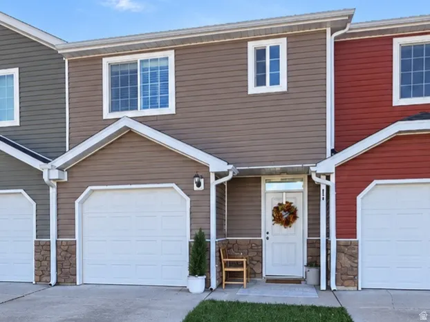 Multi-colored siding exterior with white trim, attached garages, and a concrete driveway