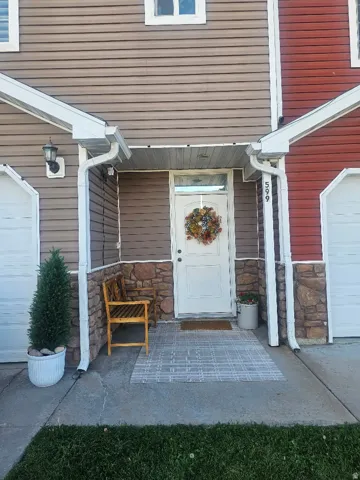 Covered entryway with a white door, horizontal siding, and stone accents