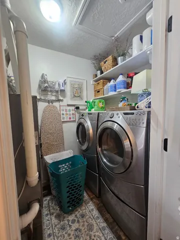 Dedicated laundry area featuring dual appliances and built-in shelving