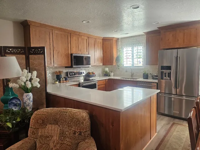 Warm wood cabinetry with stainless steel appliances, white quartz countertops, and a spacious island with seating