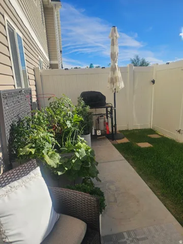 Exterior patio area featuring a concrete pathway, a privacy fence, and a grassy section