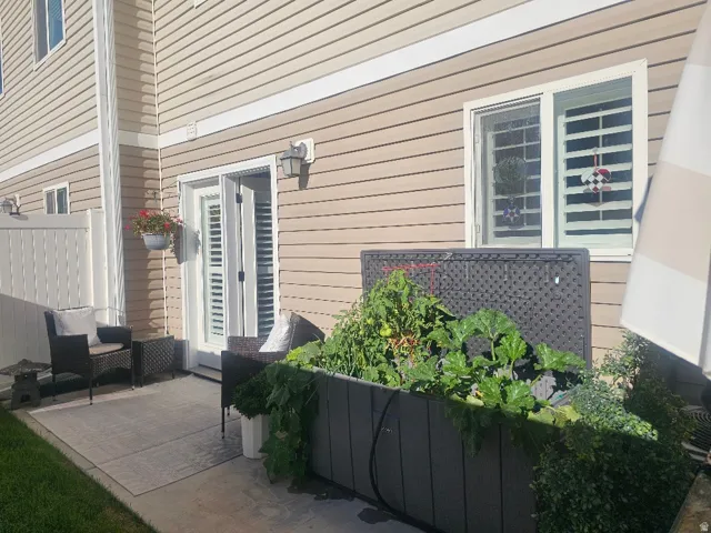 Private patio featuring a concrete slab, vinyl privacy fencing, and exterior wall siding