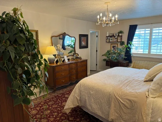 Elegant chandelier, window with plantation shutters, wood-finish dresser, and interior door access