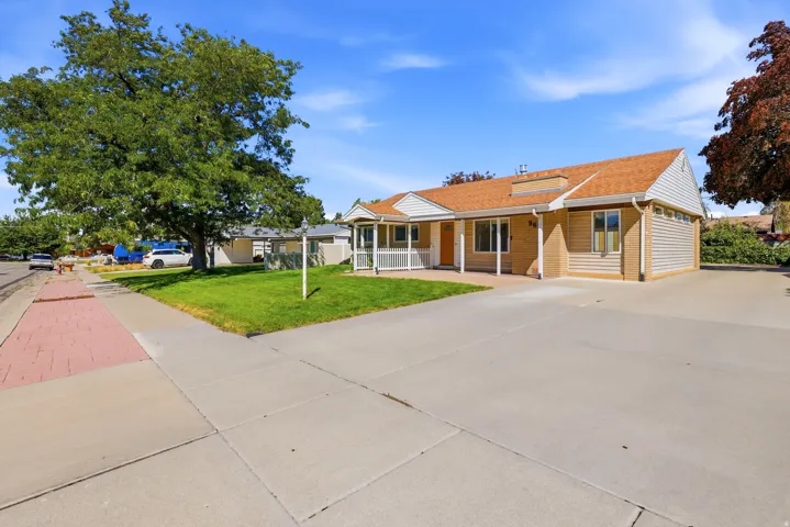 Mature landscaping, concrete driveway, and covered porch entry