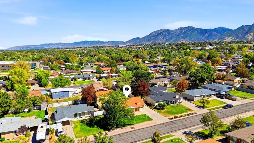 Residential neighborhood with mature trees, established landscaping, and mountain backdrop