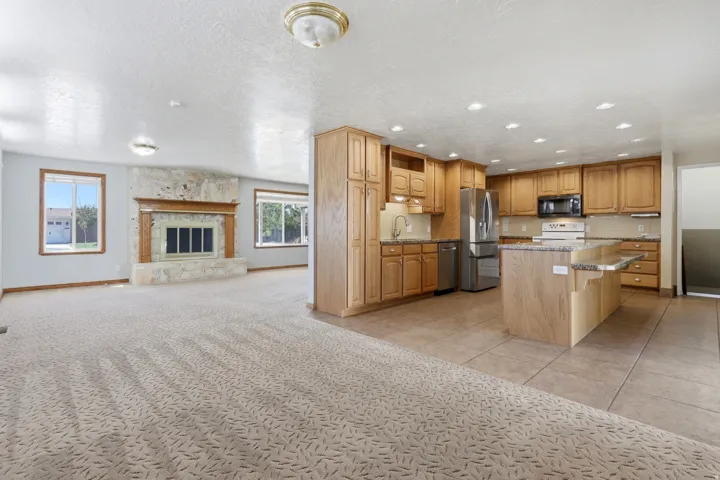 Spacious open-concept layout featuring a kitchen with wood cabinetry, stainless steel appliances, and an island with a breakfast bar
