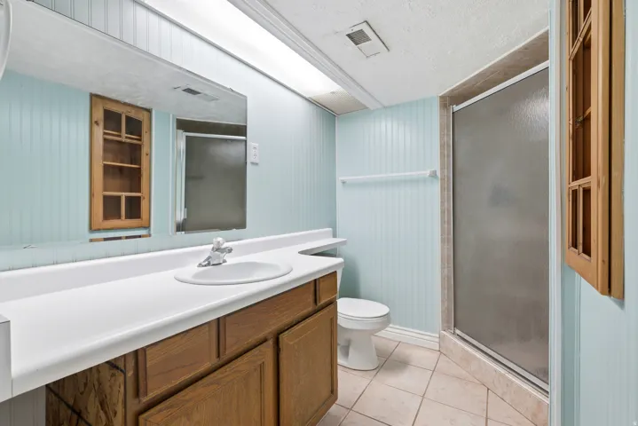 Bathroom featuring a single vanity with wood-finish cabinetry, a white countertop, and an integrated sink