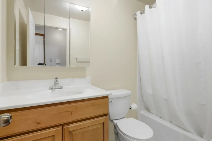 Bathroom featuring a light wood-finish vanity, integrated sink, white countertop, and mirrored medicine cabinet
