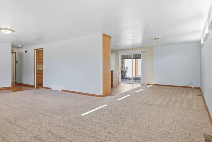 Expansive carpeted area with neutral walls, ceiling-mounted lighting, and wood-finish trim