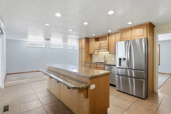 Kitchen featuring an entertainment island, wood cabinetry, stainless steel appliances, recessed lighting, and tile flooring