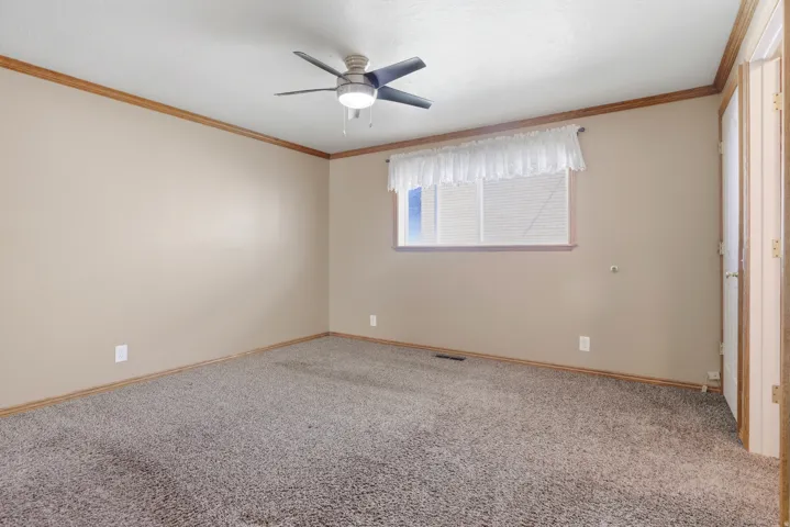 Neutral wall paint, ceiling fan with integrated lighting, window with blinds, wood-finish trim