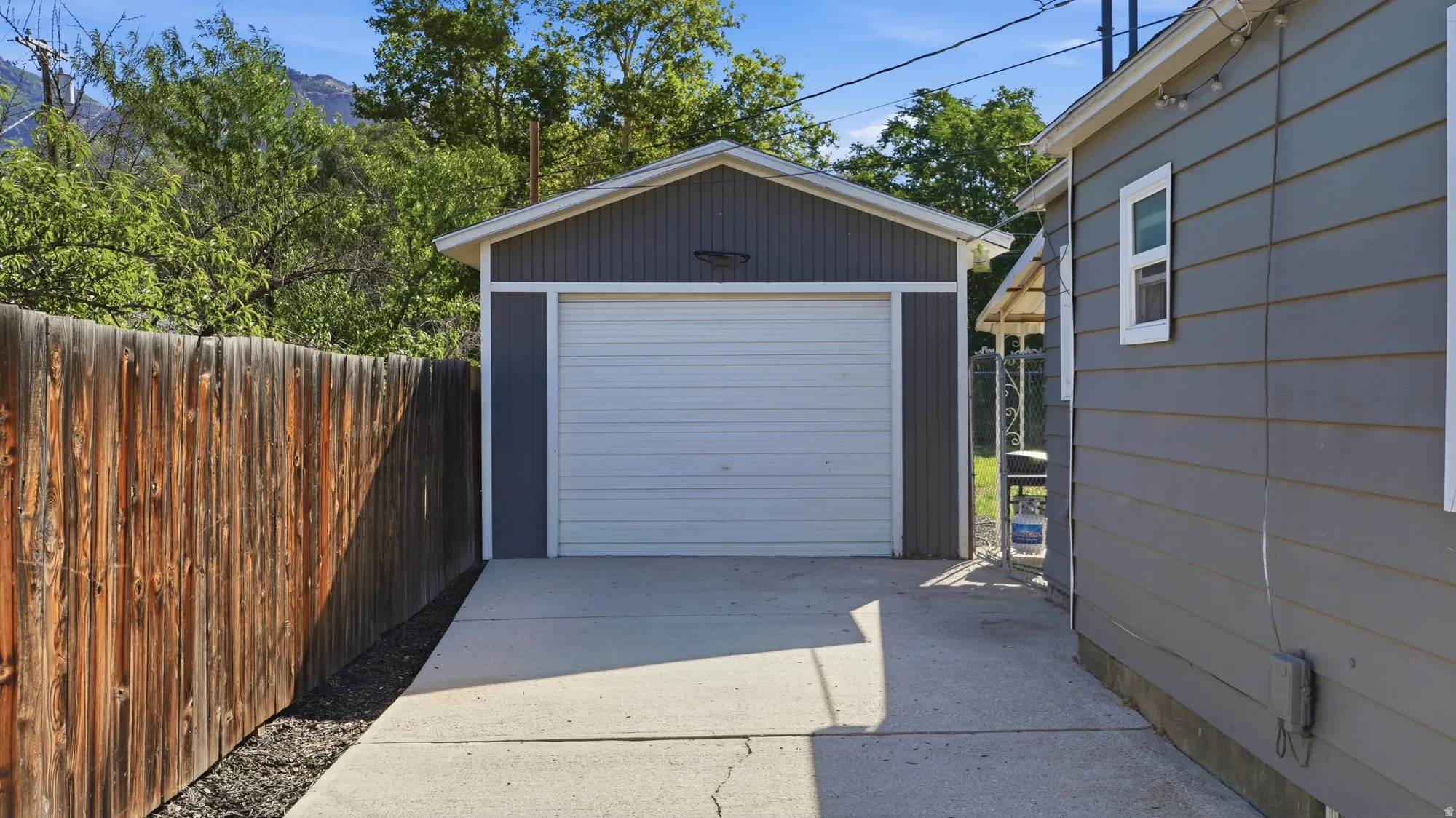 Detached garage with horizontal siding, concrete driveway, and wood fence