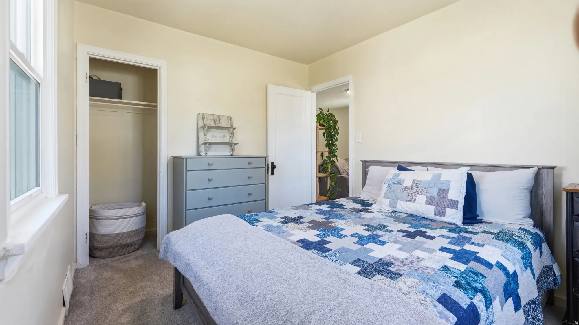 Carpeted flooring, a spacious closet with built-in shelving, and a bright window