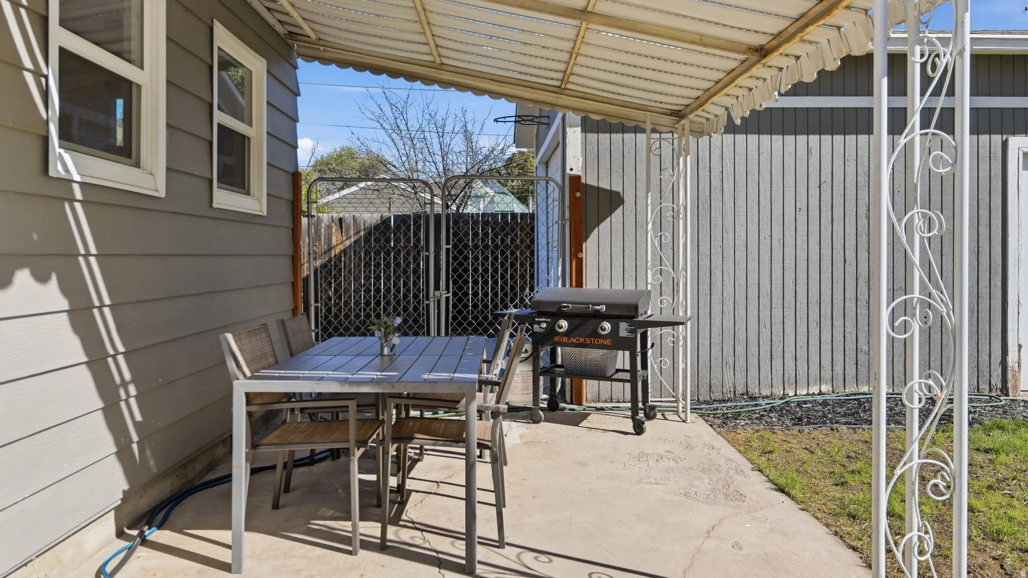 Covered concrete patio featuring decorative metal supports, horizontal siding, and multiple windows