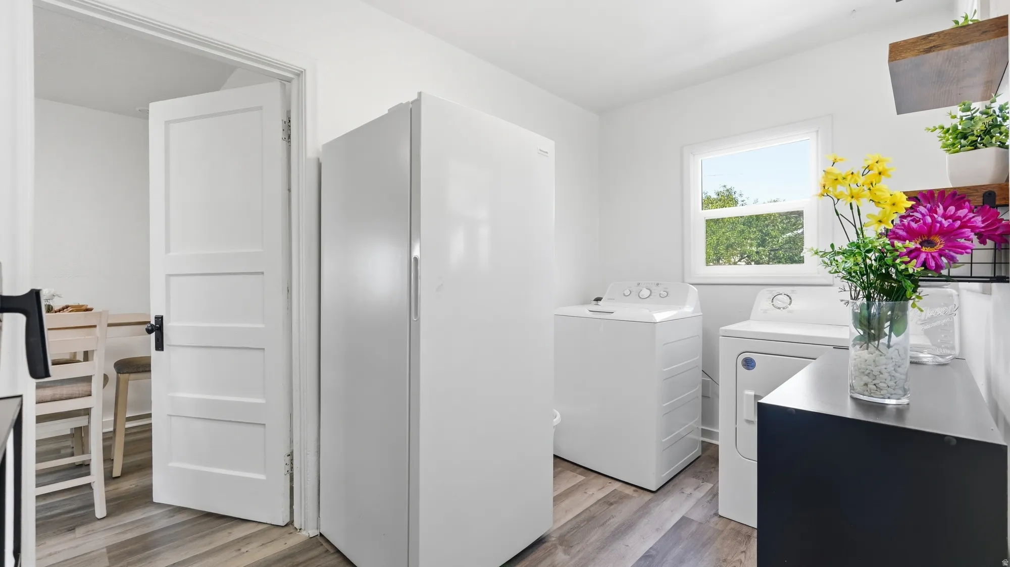 Bright utility area featuring wood-finish flooring, white walls, and a window
