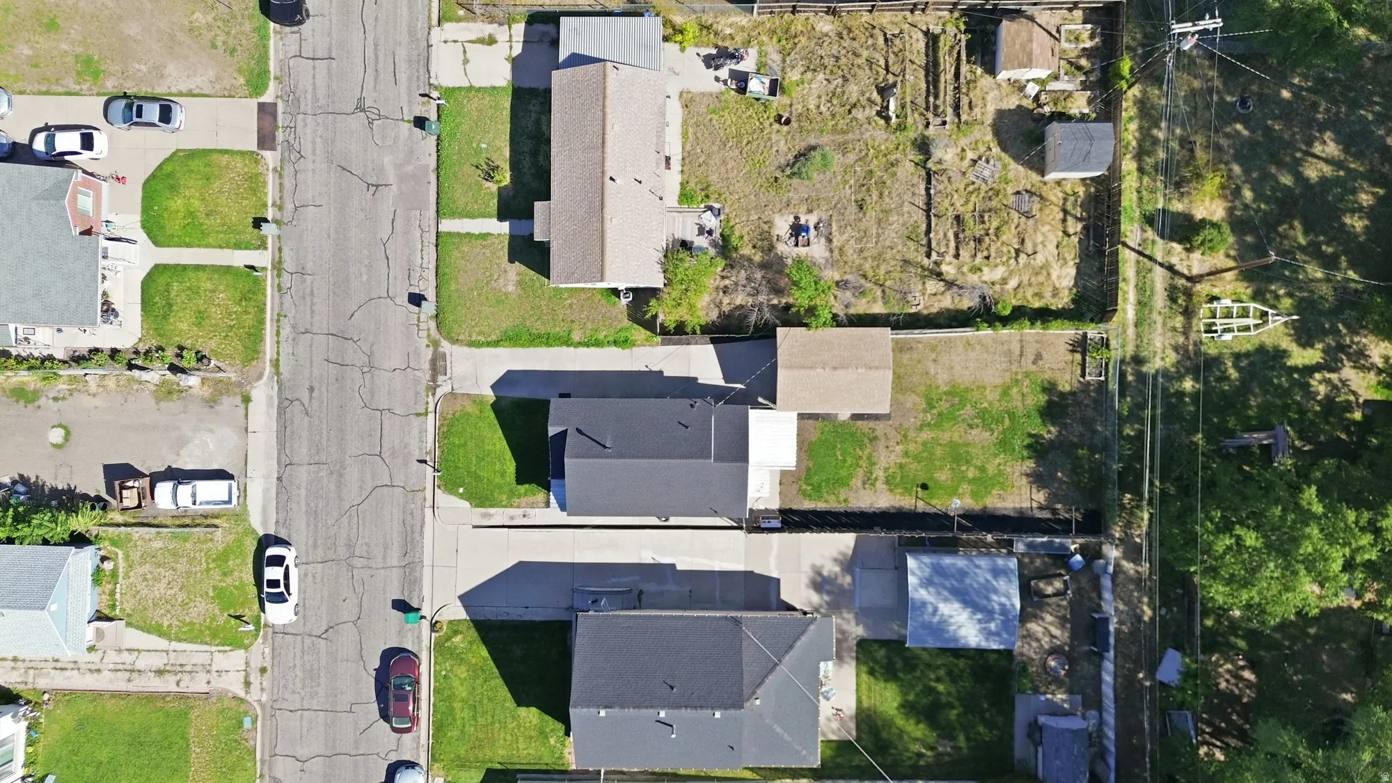 Residential property with a dark shingle roof, paved driveway, and established green lawn