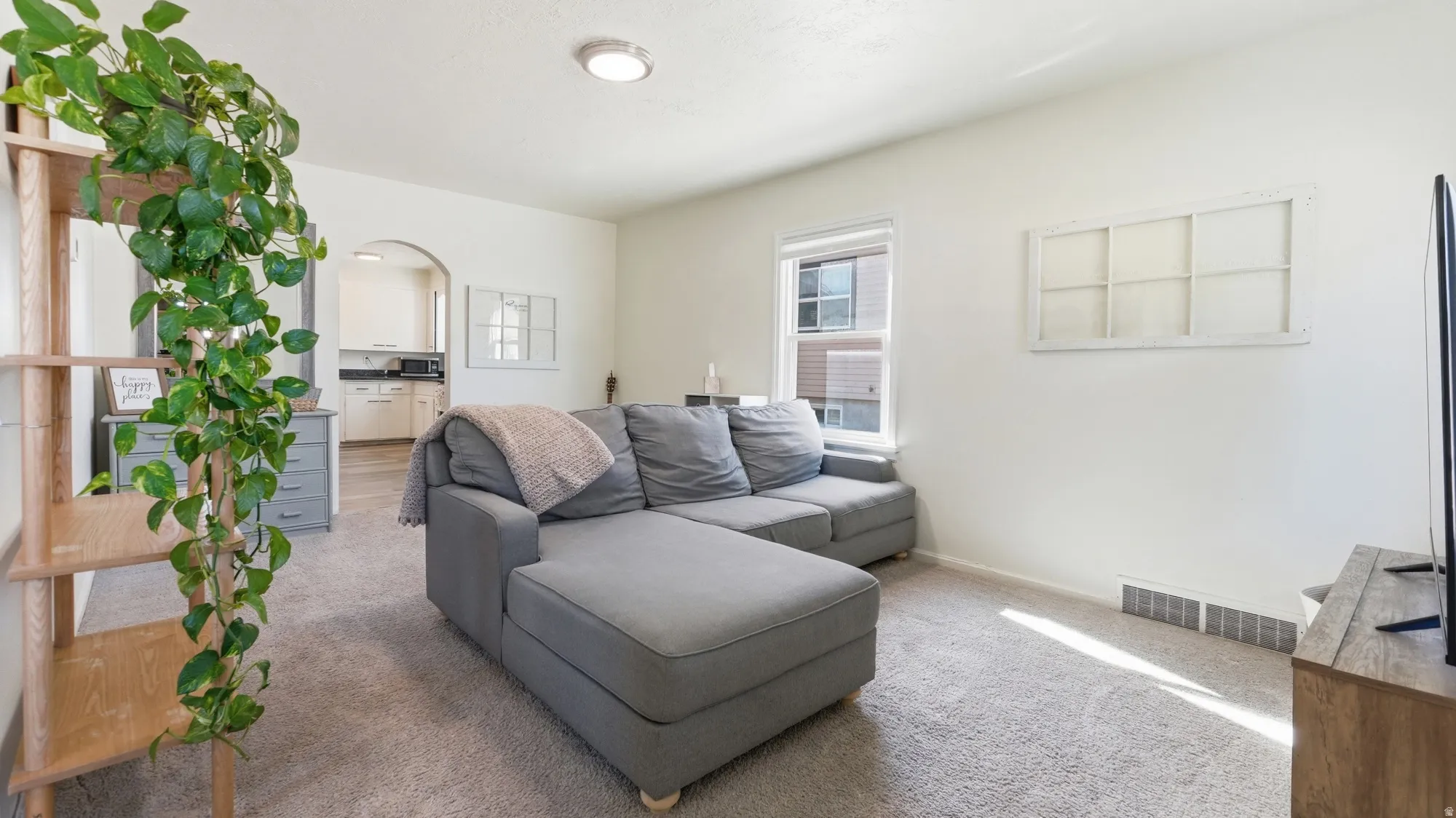 Carpeted living space with a window, arched entryway, and recessed lighting
