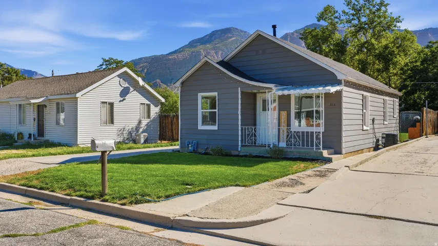 Siding exterior with a covered front porch featuring a metal awning and decorative railing