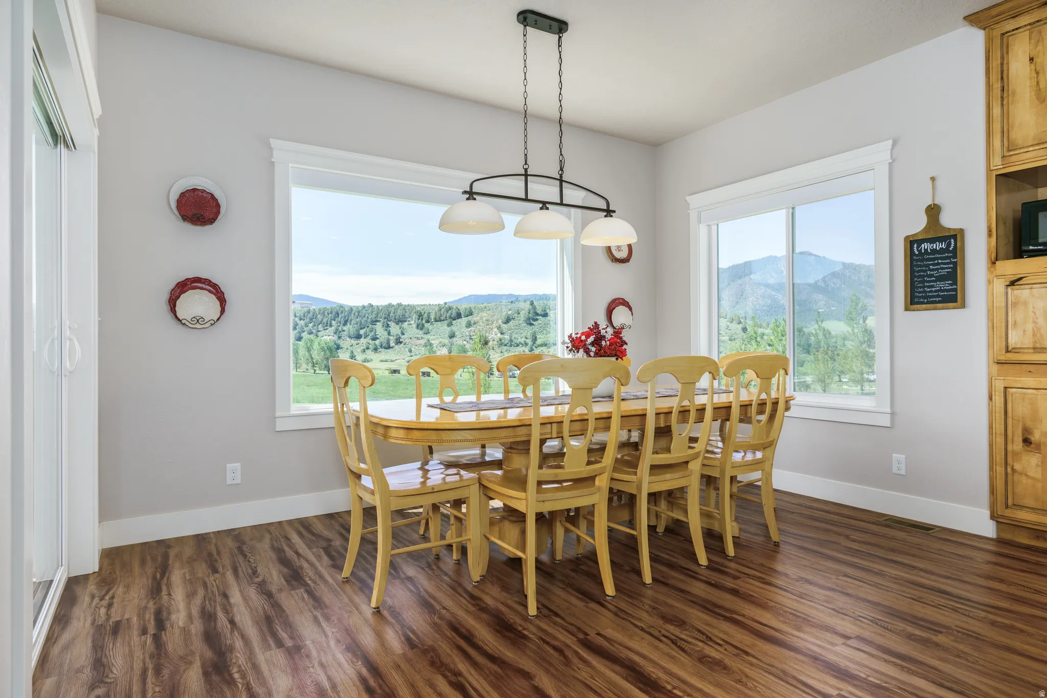 Expansive windows, wood-finish flooring, built-in wooden cabinetry, and a multi-bulb chandelier