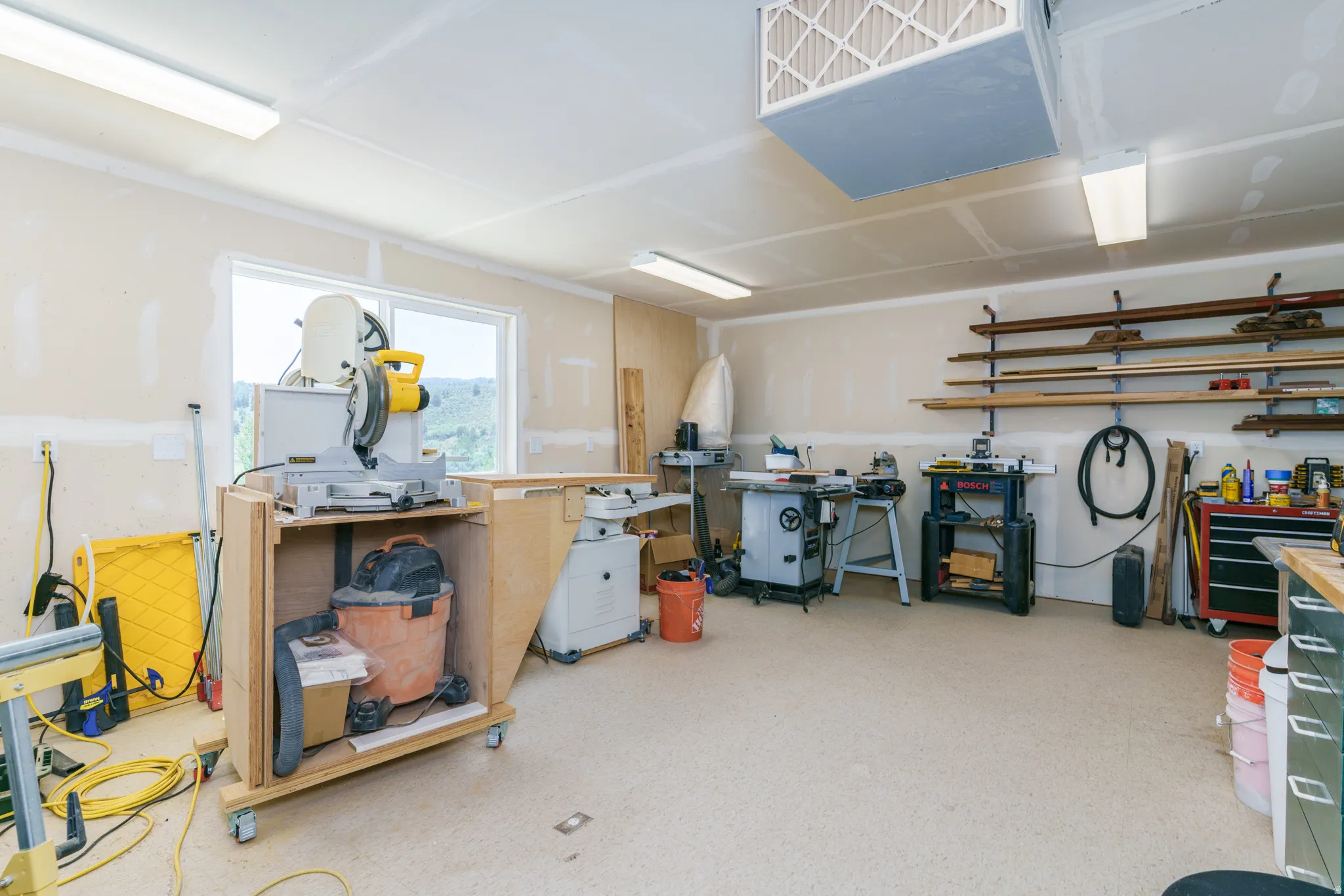 Spacious work area featuring multiple windows, recessed lighting, and wall-mounted shelving