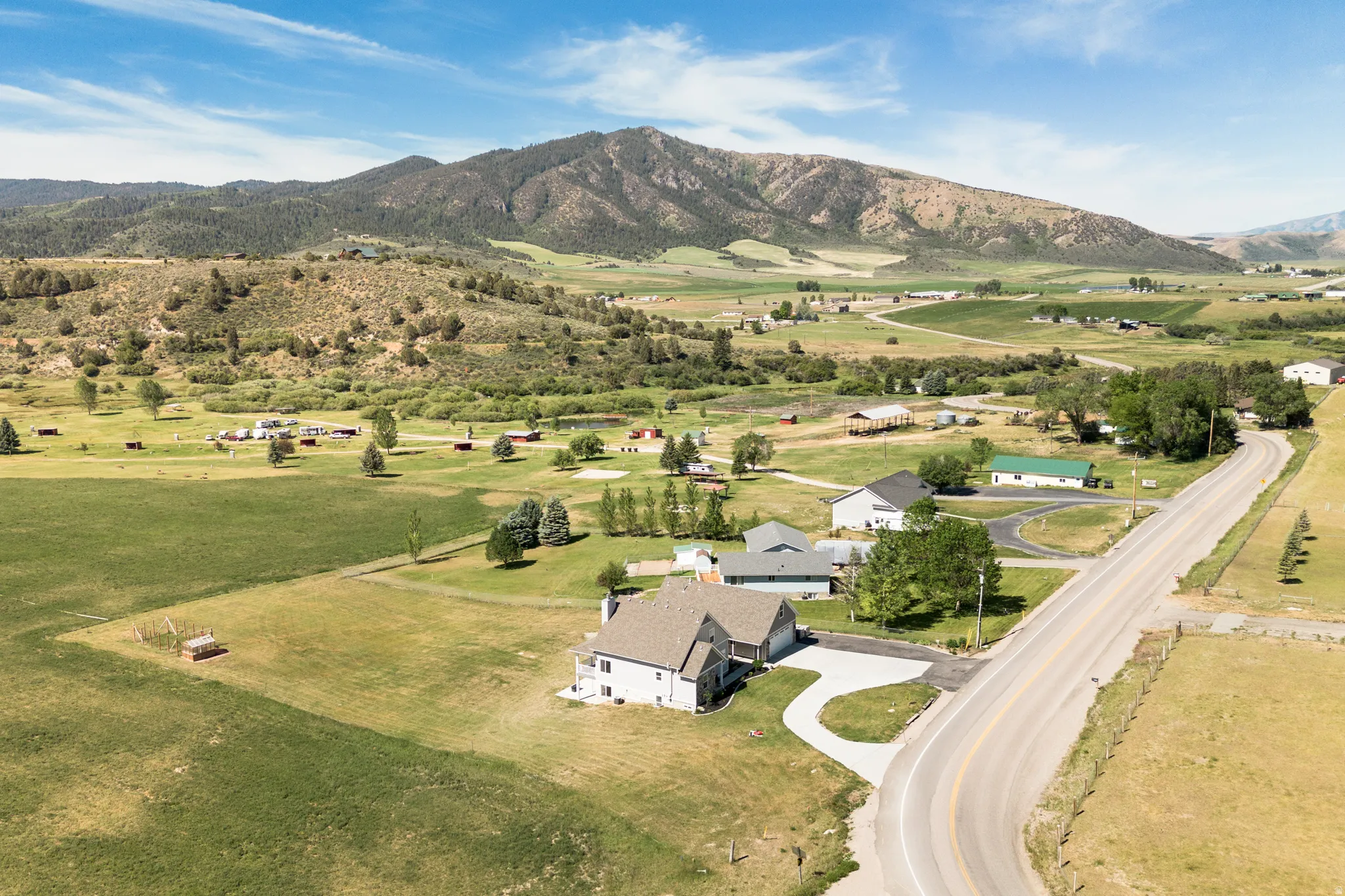 Property situated on an expansive lot with surrounding green fields and a mountain backdrop