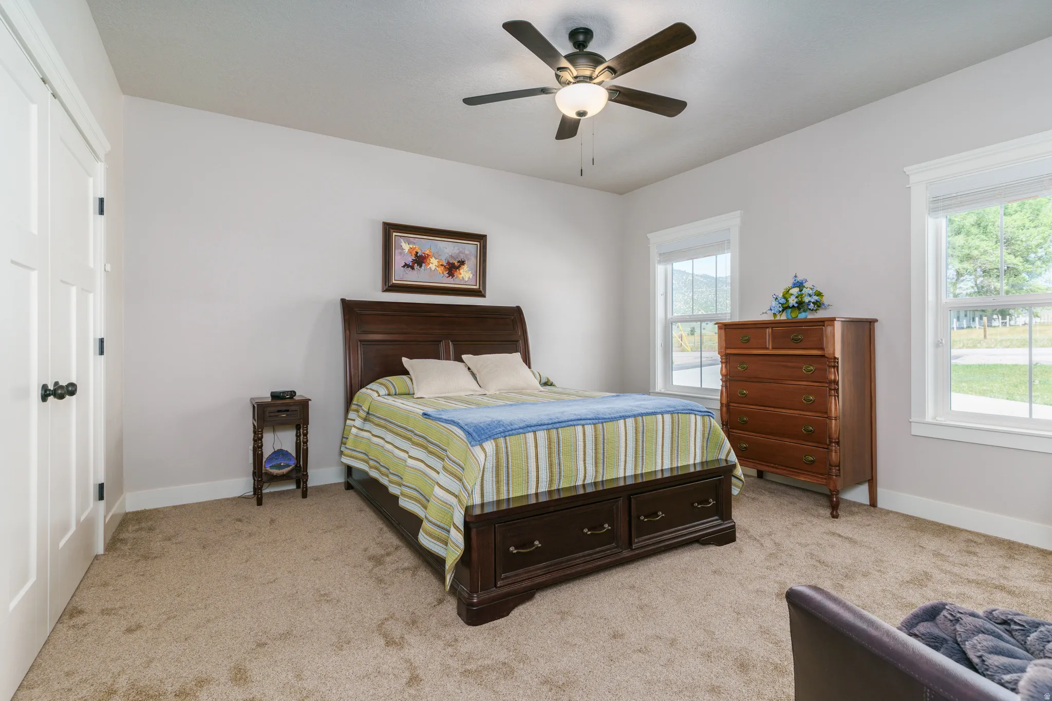Carpeted room with white trim, two windows, and a ceiling fan with integrated lighting
