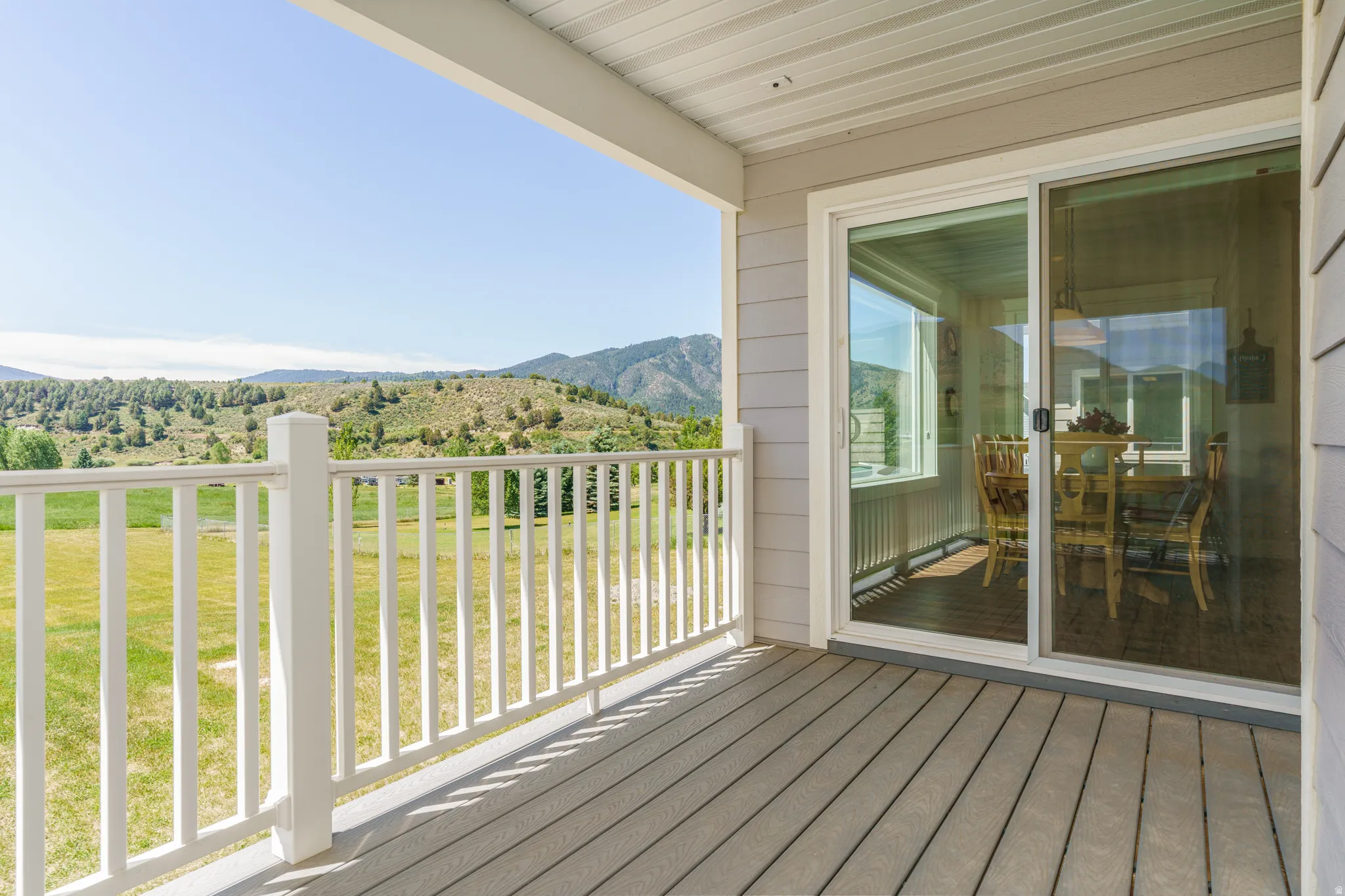 Outdoor deck with wood-finish flooring, white railing, and sliding glass door