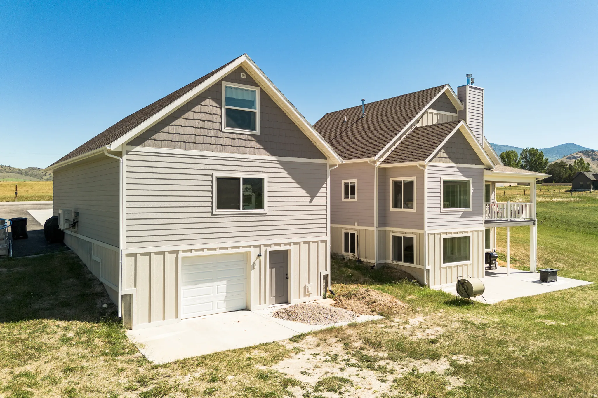 Two-story residence with a covered balcony, an attached garage, a full lower level, and a concrete patio