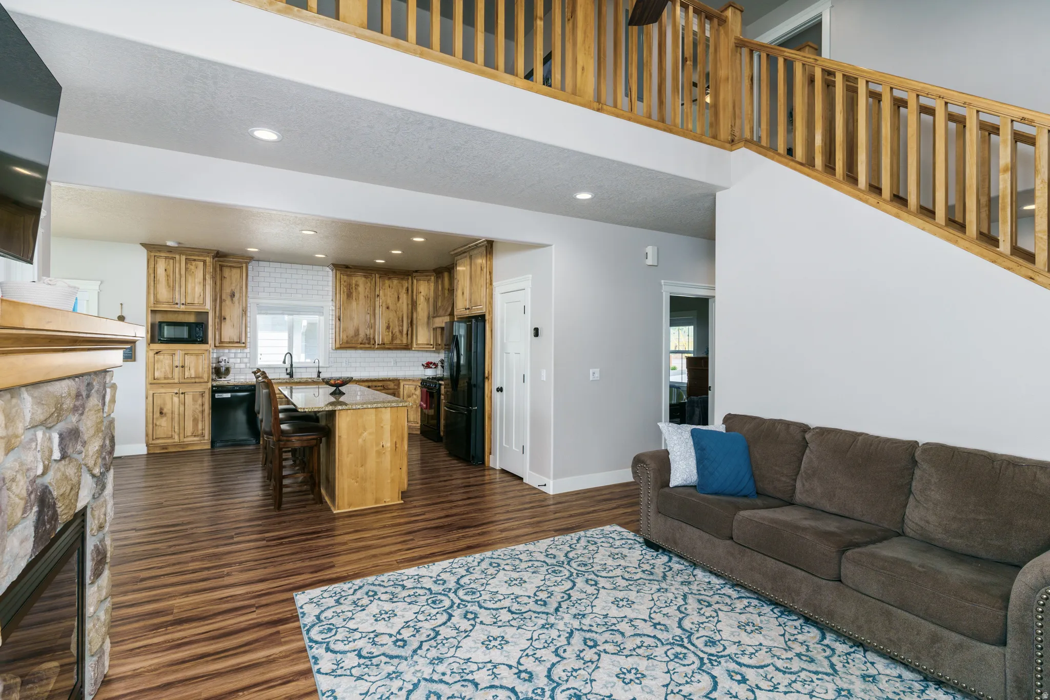 Open concept living area featuring wood-finish flooring and a stone-clad fireplace