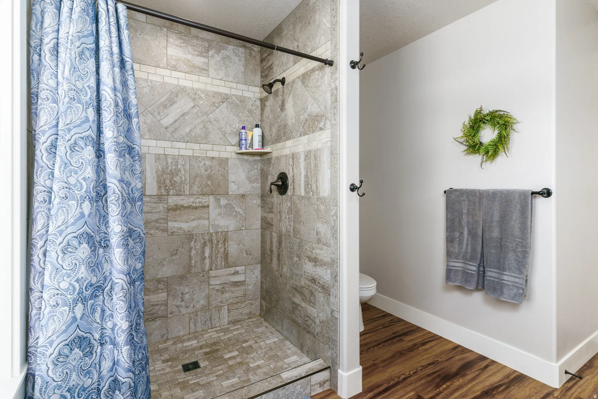 Tiled shower with a built-in corner shelf and bronze-finish fixtures